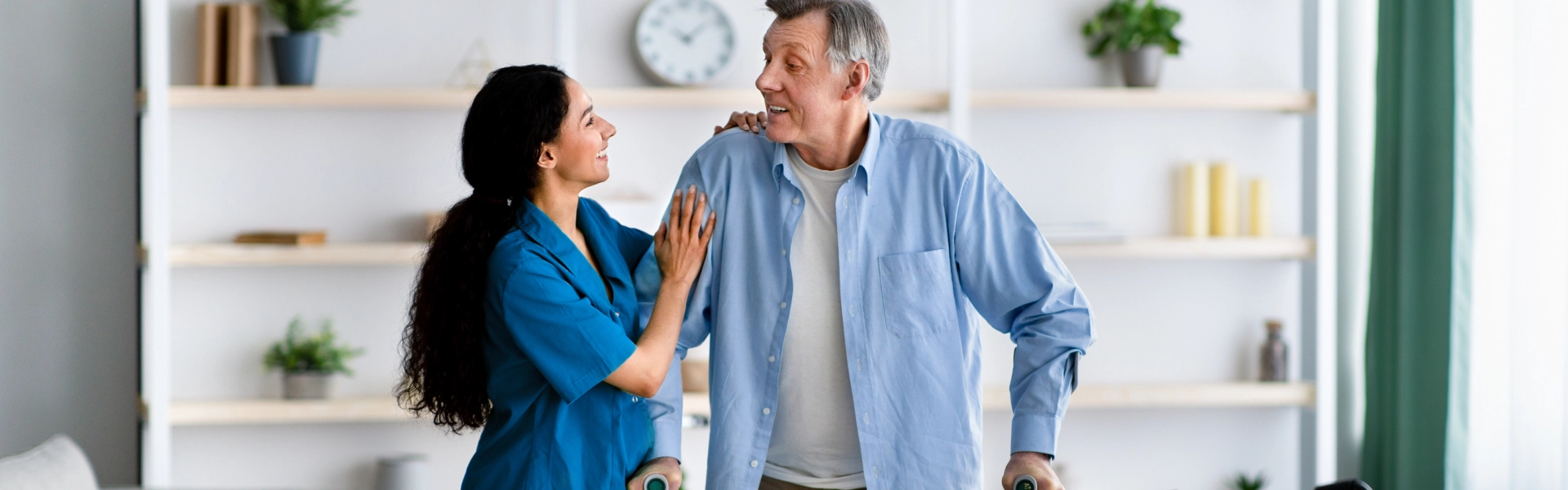 female caregiver assisting an elderly man walking