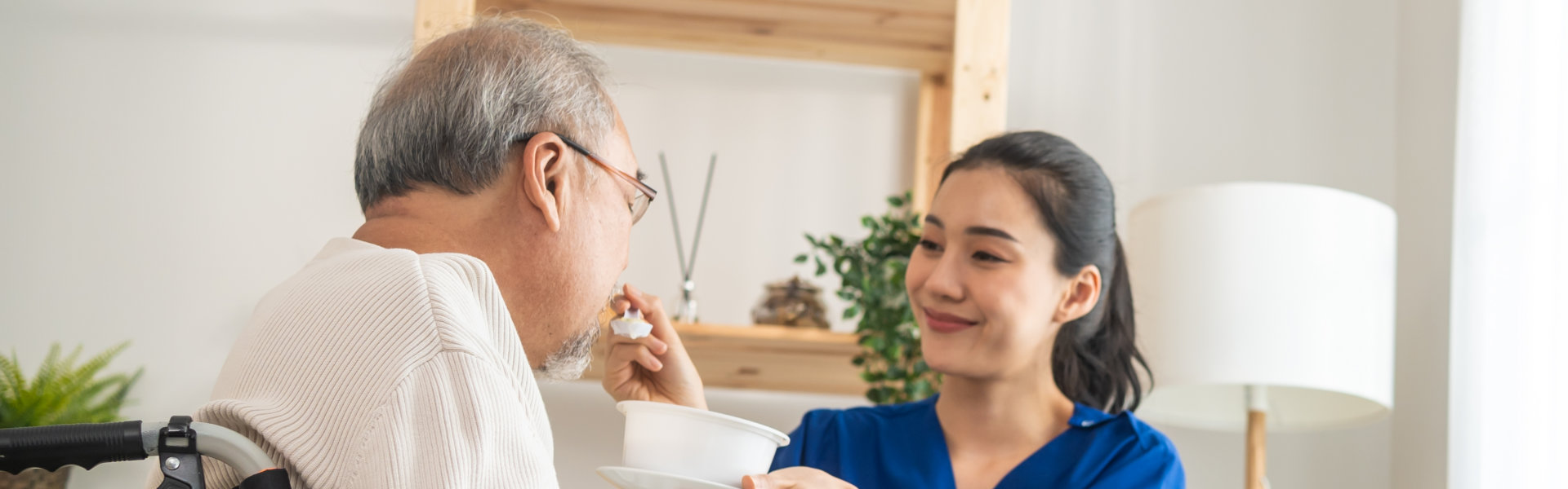 female caregiver feeding an elderly man