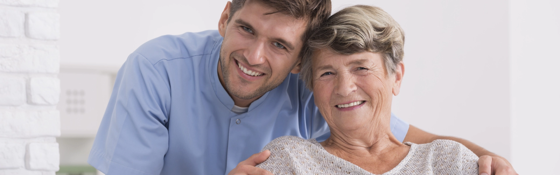 male caregiver with elderly woman smiling